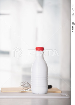 Bottle of milk with a hand whisk on the table 80617490