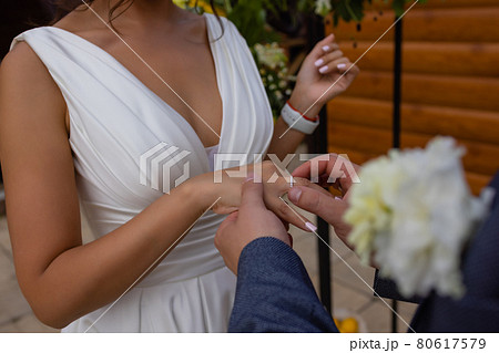 Bride putting a wedding ring on groom's finger. 80617579