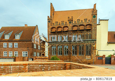 Wismar, Germany. Historic red brick buildings, brick parapet in the foreground, beautiful street lights 80617819