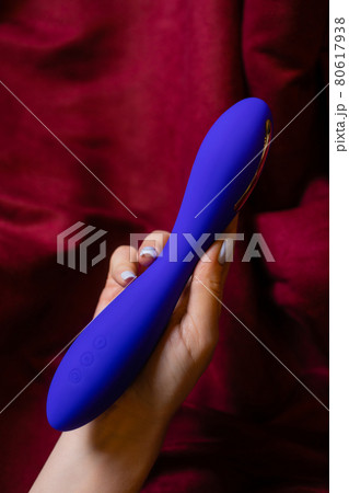 Woman in bedroom holding vibrator in hand. Woman in bedroom holding vibrator in hand. 80617938