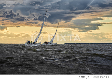 Competition of two sailboats on the horizon in sea at sunset, the amazing storm sky of different colors, race, big waves, sail regatta, cloudy weather, only main sail, sun beams Competition of two sailboats on the horizon in sea at sunset, the amazing storm sky of different colors, race, big waves, sail regatta, cloudy weather, only main sail, sun beams 80619241