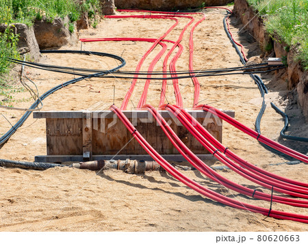 Cables with red electrical insulation lay underground near the distribution building. Cables with red electrical insulation lay underground near the distribution building. 80620663