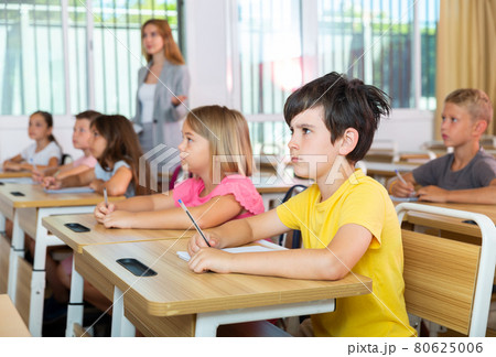 Schoolkids sitting at desks Schoolkids sitting at desks 80625006