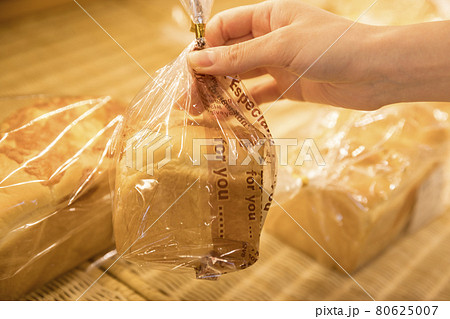 パン屋さんでパンを手にする若い女性手元 80625007