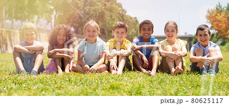 Happy team of friends children resting on grass at sunny day 80625117