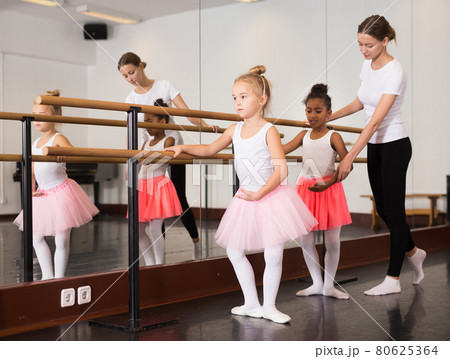 Ballet trainer teaching two little girls Ballet trainer teaching two little girls 80625364