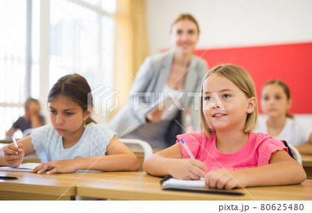 Two positive small school girls sitting together in classroom Two positive small school girls sitting together in classroom 80625480