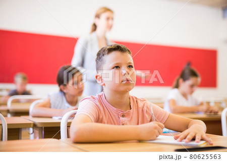 Boy and classmates sitting in classroom 80625563