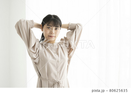 窓際で髪の毛を束ねる若い女性 窓際で髪の毛を束ねる若い女性 80625635