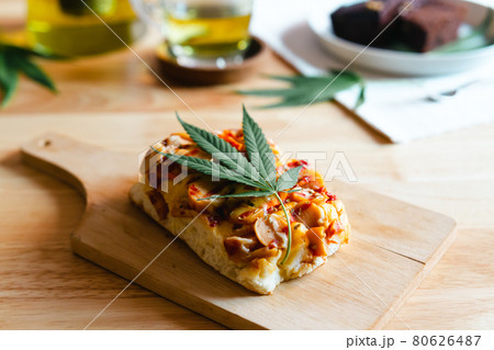 Homemade pizza with marijuana or cannabis leaf on wooden tray. 80626487