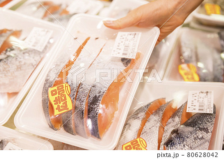 冷凍の鮭の切り身を手に取る若い女性手元 80628042