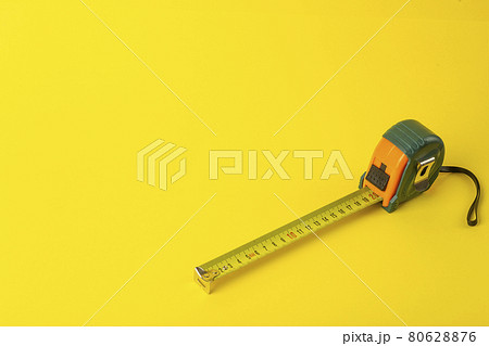 Repair, construction and tools background. Measuring tape on a yellow background. Copy space 80628876