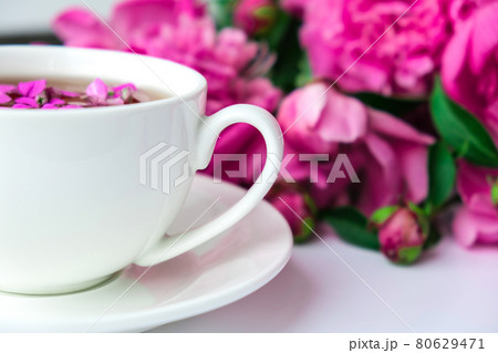 Creative layout with pink peonies flowers and cup of tea on bright table. Spring Seasonal valentine, woman, mother, 8 march holiday, romance breakfast. Stylish blogger. Greeting card Creative layout with pink peonies flowers and cup of tea on bright table. Spring Seasonal valentine, woman, mother, 8 march holiday, romance breakfast. Stylish blogger. Greeting card 80629471