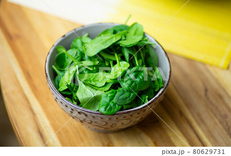 Fresh spinach leaves in a bowl on a wooden table. Eco vegan spinach salad 80629731