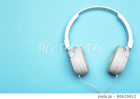 Musical headphones on a colored blue background. Aesthetics retro 80s and minimal concept Musical headphones on a colored blue background. Aesthetics retro 80s and minimal concept 80629812