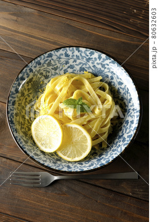 輪切りにカットされたレモンやスペアミントが乗っているレモンクリームパスタとフォークを俯瞰で撮影 80632603