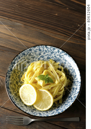 輪切りにカットされたレモンやスペアミントが乗っているレモンクリームパスタとフォークを俯瞰で撮影 80632604