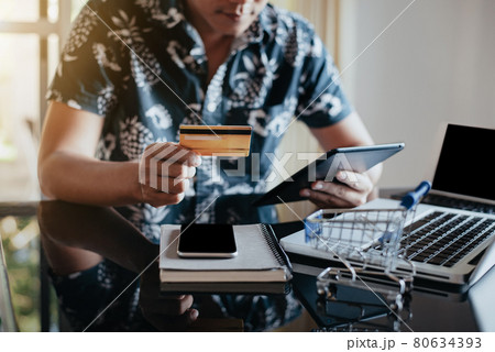 Male holding credit card and using tablet. Online shopping, e-commerce, internet banking, spending money, working from home concept. Male holding credit card and using tablet. Online shopping, e-commerce, internet banking, spending money, working from home concept. 80634393