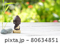 Little Buddha meditating with stones and bamboo on wooden background 80634851