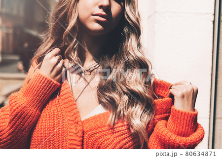 Portrait of fashionable women in orange sweater and beige dress posing in the street 80634871