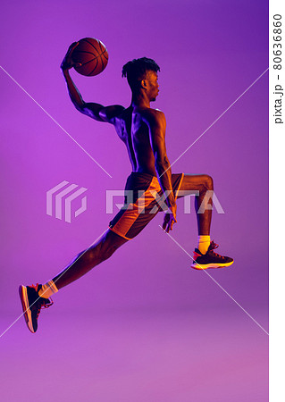Young african man, basketball player in motion with ball isolated over gradient purple neon background. Back view Young african man, basketball player in motion with ball isolated over gradient purple neon background. Back view 80636860