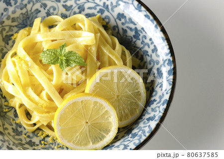 輪切りにカットされたレモンやスペアミントが乗っているレモンクリームパスタを白背景で俯瞰撮影 80637585