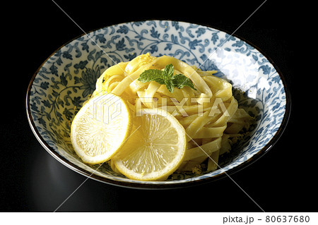 輪切りにカットされたレモンやスペアミントが乗っているレモンクリームパスタを黒背景で撮影 80637680