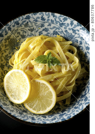 輪切りにカットされたレモンやスペアミントが乗っているレモンクリームパスタを黒背景で俯瞰撮影 80637786