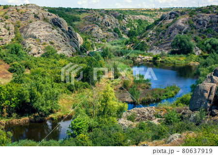 natural landscape of canyon with granite rocks on the top of the cliff on a sunny summer day, mountain curve river with lake and reeds in the valley at the foot of the valley below, nobody. natural landscape of canyon with granite rocks on the top of the cliff on a sunny summer day, mountain curve river with lake and reeds in the valley at the foot of the valley below, nobody. 80637919