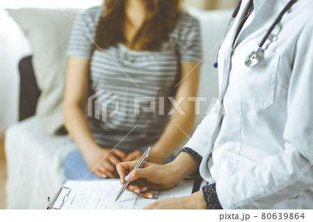 Unknown woman doctor and patient discussing current health examination while sitting in cozy living room. Stay at home concept during Coronavirus pandemic and self isolation quarantine Unknown woman doctor and patient discussing current health examination while sitting in cozy living room. Stay at home concept during Coronavirus pandemic and self isolation quarantine 80639864