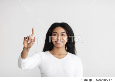 Smart home. Young african american lady pointing finger in the air pushing button on invisible screen 80640547