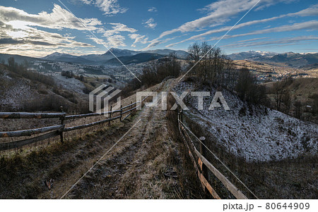 Winter coming. Last good weather days in autumn mountain countryside morning picturesque scene. Dirty road from hills to the village. Hoverla and Petros Ukrainian Carpathians mountains in far. 80644909
