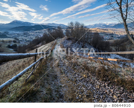 Winter coming. Last good weather days in autumn mountain countryside morning picturesque scene. Dirty road from hills to the village. Hoverla and Petros Ukrainian Carpathians mountains in far. 80644910