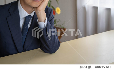 在宅ワークで考え事をするビジネスマン。頬杖をつく男性。 在宅ワークで考え事をするビジネスマン。頬杖をつく男性。 80645481
