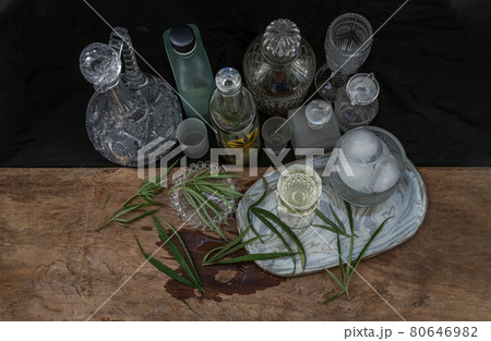 Ice cold Marijuana cannabis CBD infused drink in a crystal clear glass with green marijuana leaf on wooden background. 80646982