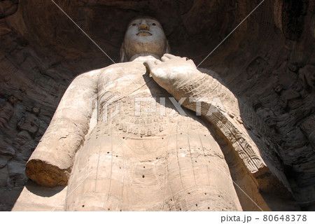 Yungang Grottoes near Datong in Shanxi Province, China. Large ancient statue of Buddha in a cave at Yungang. Standing Buddha from below. Yungang Buddhist cave art and sculptures UNESCO world heritage. 80648378