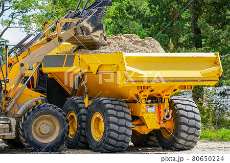 the front loader loads the sand into the dump truck the front loader loads the sand into the dump truck 80650224