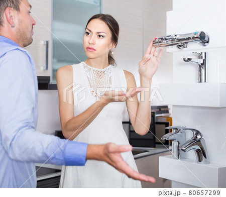 Unhappy girl communicating with seller of kitchen accessories 80657299