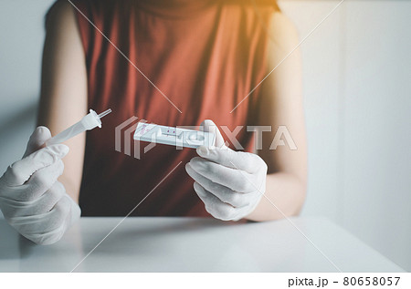 Asian patient woman using a covid-19 self test rapid antigen testing kit at home 80658057