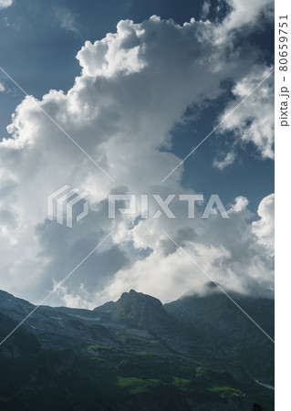 Rocks and a pass with a blue sky with sun rays breaking through the clouds. 80659751