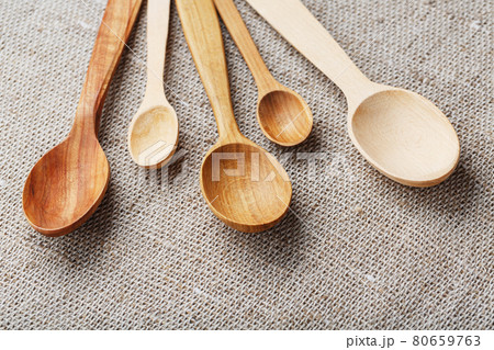 Wooden spoons made of natural wood on burlap fabric as a craft. Wooden spoons made of natural wood on burlap fabric as a craft. 80659763