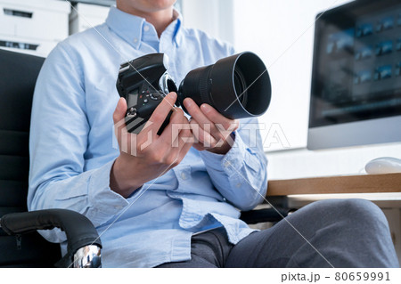 デジタル一眼レフカメラのレンズを交換する男性クリエイターの手元 80659991