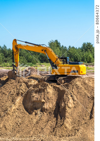An industrial yellow excavator develops in a sandpit quarry. Industry, technology, mining. Heavy An industrial yellow excavator develops in a sandpit quarry. Industry, technology, mining. Heavy 80664372