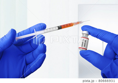 Health worker hand with gloves holding syringe and covid 19 vaccines 80666931