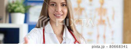 Smiling female doctor stretches out her hand for handshake in medina office Smiling female doctor stretches out her hand for handshake in medina office 80668341