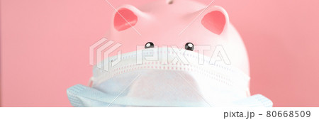 Pink pig piggy bank in protective mask and stethoscope stands on table 80668509