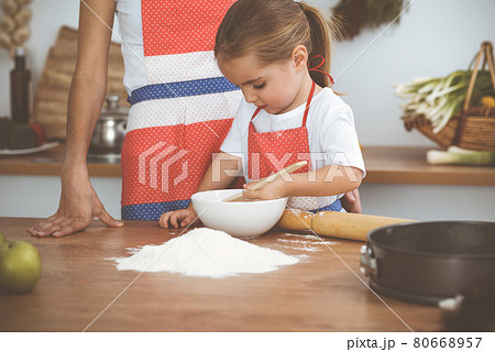 Happy woman and her daughter are kneading the dough and baking cookies for a delicious family feasting. Christmas, New year, Thanksgiving, Anniversary, Mothers Day. Healthy meal cooking concept Happy woman and her daughter are kneading the dough and baking cookies for a delicious family feasting. Christmas, New year, Thanksgiving, Anniversary, Mothers Day. Healthy meal cooking concept 80668957