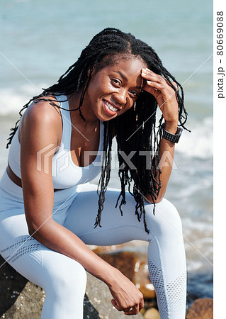 Sportswoman Resting on Rock on Beach 80669088