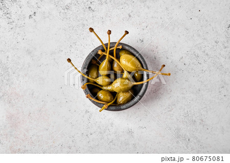 Marinated capers in bowl on light textured background. Top view 80675081