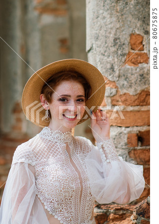 Pretty young caucasian redhead girl in a garden and outside with her wedding bouquet. Beautiful redhead bride. 80675875